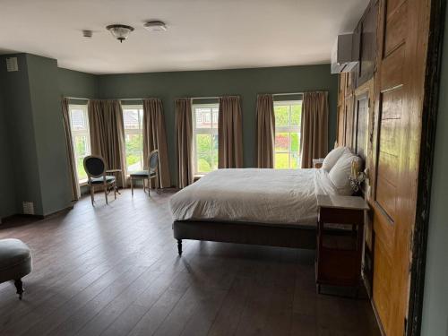 a bedroom with a bed and a desk and windows at L'Hopster Dorpsbrouwerij in Loppersum