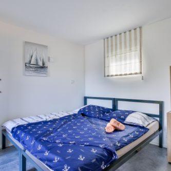 a bed with a blue sheets and two towels on it at Marina Orlík in Kowářow