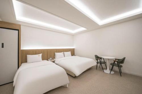 two beds in a room with a table and chairs at 드므호텔 in Changwon