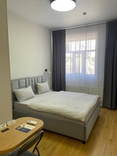 a bedroom with a bed and a table and a window at Hotel GLORIA in Ceadîr-Lunga