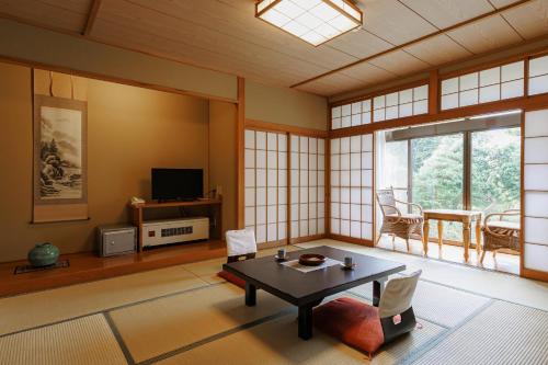 a living room with a table and a tv at Ryokan Warabino in Takayama