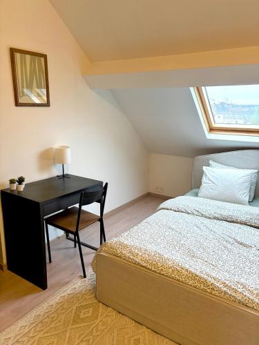 a bedroom with a bed and a desk with a window at Hébergement proche de Atomium Expo Serres Royales in Grimbergen