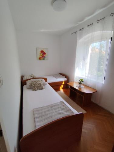 a small bedroom with a bed and a window at Apartments Milevčić in Jelsa