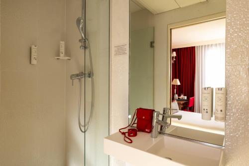 a bathroom with a shower and a red bag on a sink at Hotel Des Deux Continents in Paris