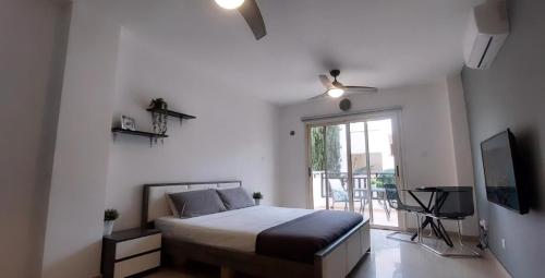 a bedroom with a bed and a tv and a window at Modern Studio apartment Armonia Court in Paralimni