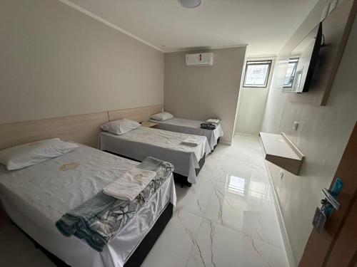 a small room with two beds and a mirror at Hotel Impactus Santo Amaro in São Paulo