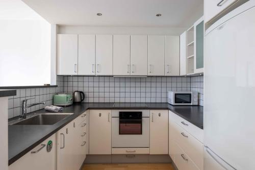 a kitchen with white cabinets and black counter tops at Amazing Two Bedroom Apartment in Urban Area in Copenhagen