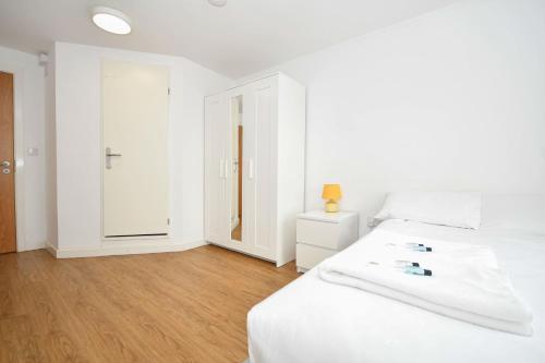 a white bedroom with a white bed and wooden floors at Cosy Budget En-suites, Optional Kitchen, Liverpool in Liverpool