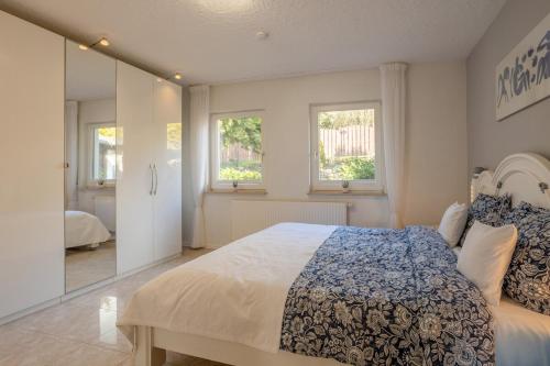 a bedroom with a large bed and two windows at Green Eifel Casa in Feusdorf