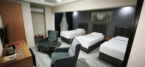a small room with two beds and a chair at Lantis Otel in Avcılar