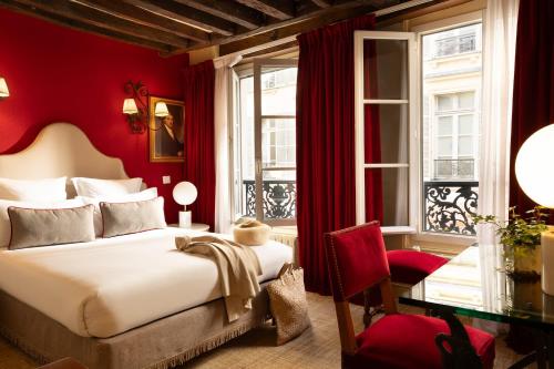 a bedroom with a bed and a desk and windows at Hotel Des Deux Continents in Paris