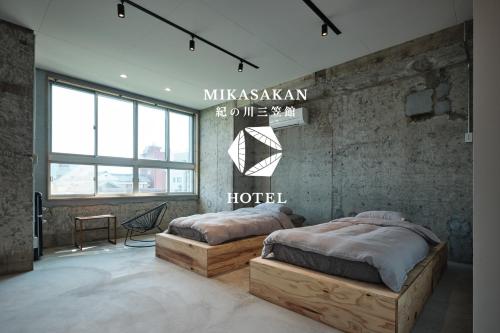 a bedroom with two beds and a sign on the wall at 三笠館Mikasakan 別館 in Kinokawa