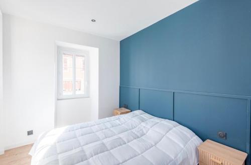 a bedroom with a large bed with a blue wall at La Belle Echappée - Superbe T2 en Hyper Centre in Thonon-les-Bains