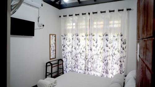a bedroom with a bed and a window with a curtain at Premier Villa Tangalle in Tangalle