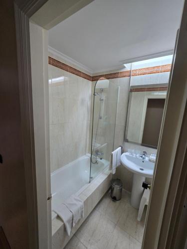 a bathroom with a bath tub and a sink at Hotel Las Sirenas in Viveiro