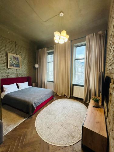 a bedroom with a bed and a rug and windows at Apart hotel на Франка by Willox in Chernivtsi