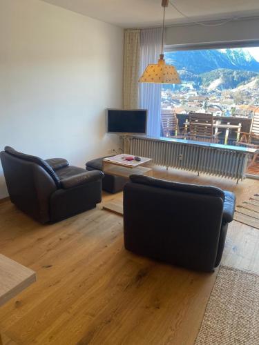 a living room with two chairs and a couch and a television at Appartement Raineck in Mittenwald