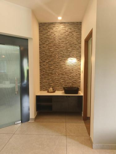 a bathroom with a sink and a brick wall at The Riverside Nook Calicut in Kozhikode