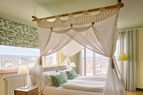 a bedroom with a canopy bed with a large window at Hotel Viva Sky in Konstanz