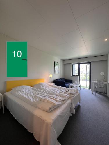 a large bed in a room with a green sign on the wall at Hotel Margrethe in Gadbjerg