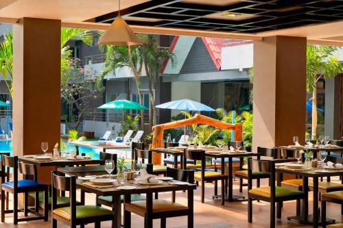 a restaurant with tables and chairs and a pool at The Holiday Resort Pattaya in Pattaya