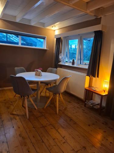 a dining room with a table and chairs and two windows at Apartment Claeswael in Klaaswaal