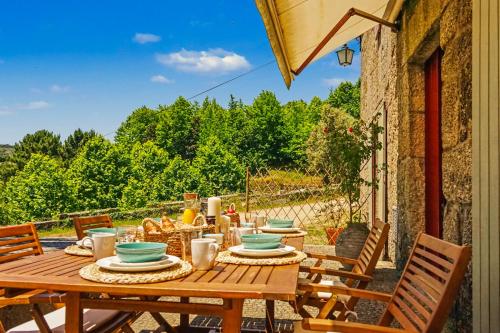 a wooden table with plates of food on a patio at Quinta de Travanca - Casa da Eira in Baião