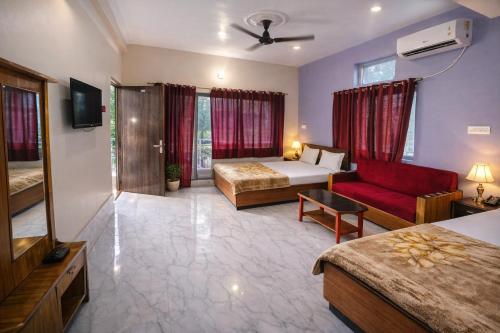 a hotel room with two beds and a red couch at Hotel Baba Palace in Deoghar