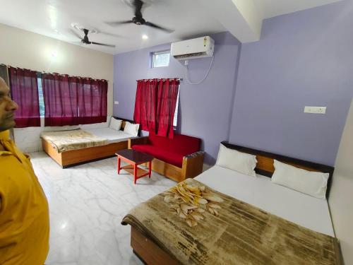 a man standing in a room with two beds at Hotel Baba Palace in Deoghar