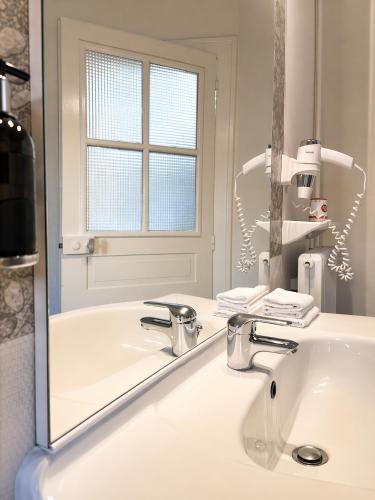 a white bathroom with a sink and a mirror at Logis Hotel restaurant de la Poste in Pontgibaud