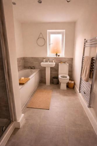 a bathroom with a tub and a toilet and a sink at Bright & Spacious 3-Bed Rotherham Home Ideal for Families or Contractors in Kimberworth