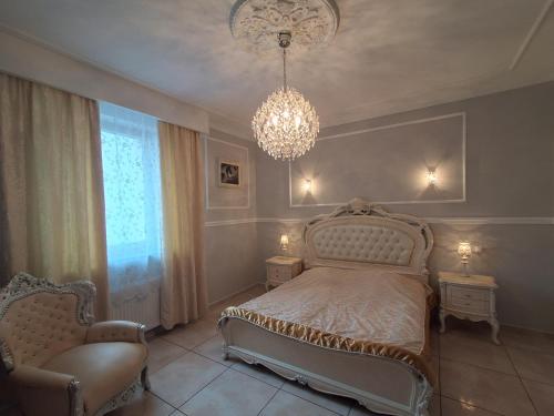 a bedroom with a bed and two chairs and a chandelier at Pensjonat Sielec in Sosnowiec