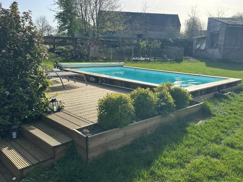 ein Schwimmbad mit Holzdeck und Bänken in der Unterkunft Envoz-Zen in Héron