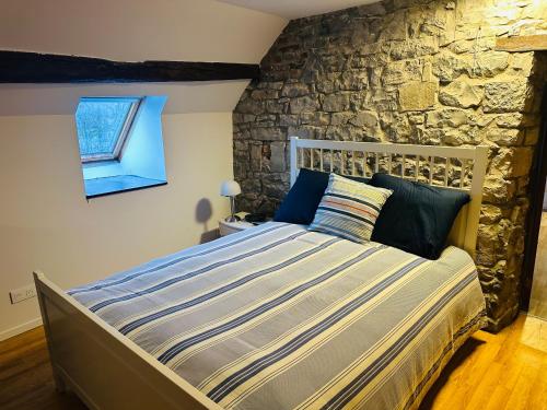 ein großes Bett in einem Zimmer mit einer Steinwand in der Unterkunft Envoz-Zen in Héron