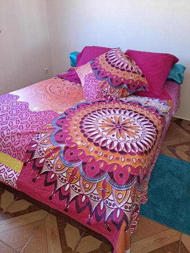 a bed with a colorful blanket and pillows on it at KANALU in Bouillante