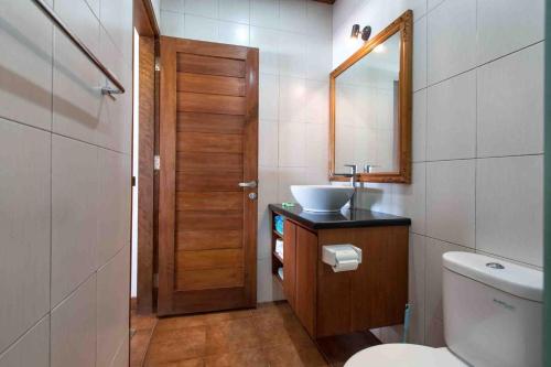 ein Badezimmer mit einem Waschbecken, einem WC und einem Spiegel in der Unterkunft Kainalu Beach House in Nusa Lembongan