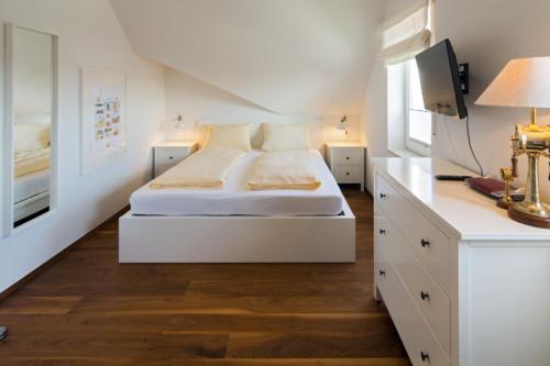 a white bedroom with a bed and a desk at Ferienwohnung Loft in Strandnähe in Norden