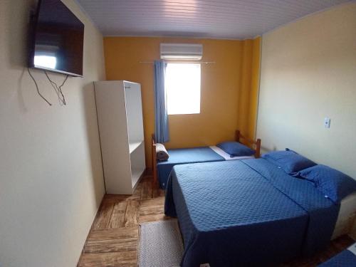 a small room with two beds and a refrigerator at Pousada São Benedito CP in Cachoeira Paulista
