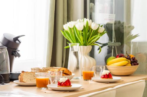 a table with breakfast foods and a vase of flowers at Le Sauge - Studio climatisé - Cocon rénové in Agen
