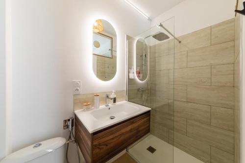 a bathroom with a sink and a toilet and a mirror at Le Brun - T1 climatisé - Terrasse et jardin privé in Agen