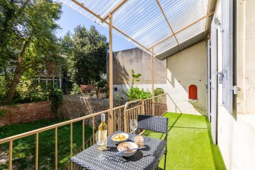 a table and chairs on a balcony with a glass roof at Le Brun - T1 climatisé - Terrasse et jardin privé in Agen