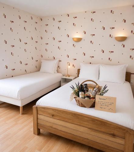 two beds with a basket on top of them in a room at Logis Hotel restaurant de la Poste in Pontgibaud