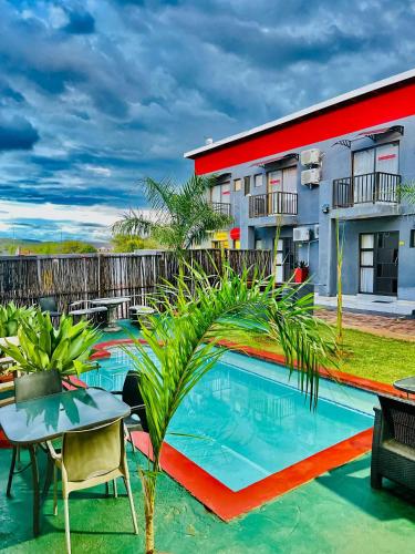 a pool with a table and chairs and a building at Clifford's Rufaro Hotel, Conference & Spa in Burgersfort