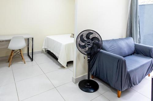 a fan in a living room next to a blue couch at Studio Completo c Wifi perto do Centro de Itabuna in Itabuna