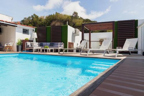 a swimming pool with chairs and a table at The Spot - ilha de São Miguel (Povoação) Açores in Povoação