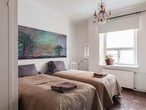 a bedroom with two beds and a painting on the wall at Artist Apartment Susi in Helsinki