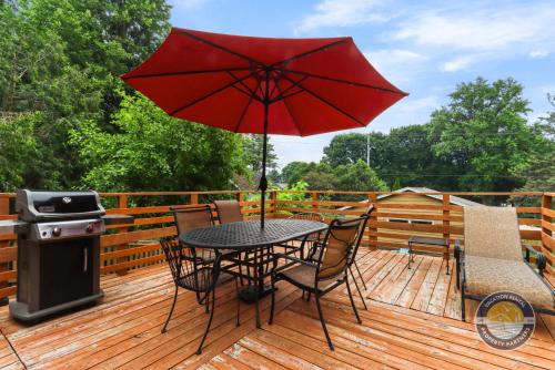a patio table with a red umbrella on a deck at Charming Pet-Friendly Lake Retreat in Lake Geneva