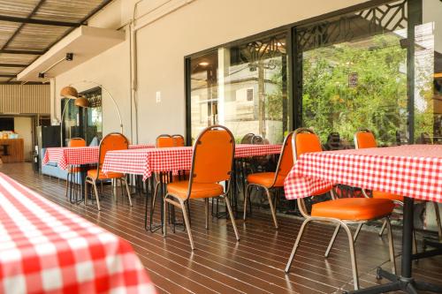 an empty restaurant with red and white tables and chairs at Chaba Inn Srinakarin in Bangna