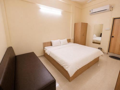 a bedroom with a bed and a stool in it at Hotel Shreenath Heritage in Ujjain