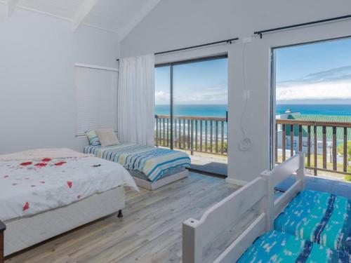 a bedroom with a bed and a balcony with the ocean at Ocean View 147 in Struisbaai